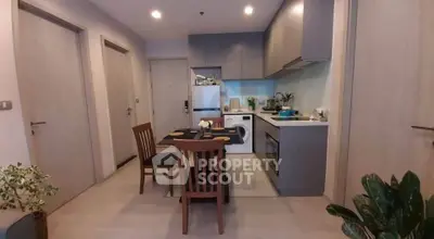 Modern kitchen with dining area featuring sleek cabinetry and integrated appliances in a cozy apartment.