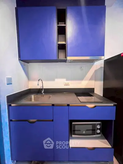 Modern compact kitchen with blue cabinets and built-in microwave