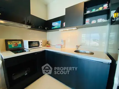Modern kitchen with sleek black cabinets and built-in appliances, featuring a microwave and stylish decor.