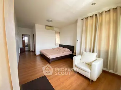 Spacious bedroom with wooden flooring and cozy seating area