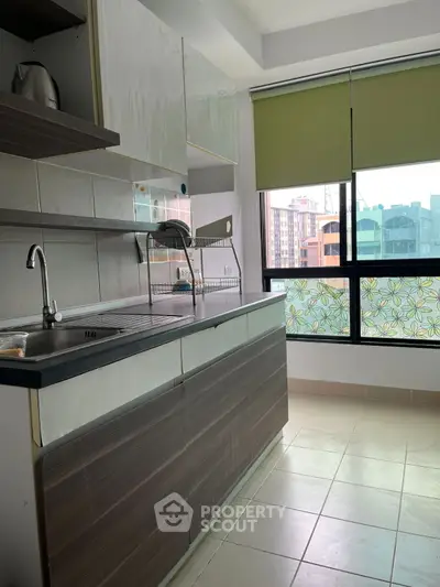 Modern kitchen with sleek cabinets and large window offering city view.