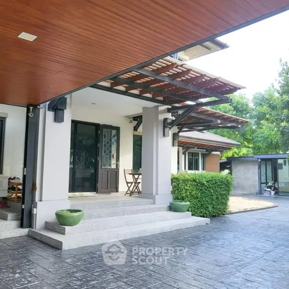 Modern home entrance with stylish wooden ceiling and lush greenery