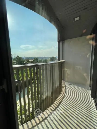 Spacious balcony with stunning view of greenery and cityscape, perfect for relaxation.