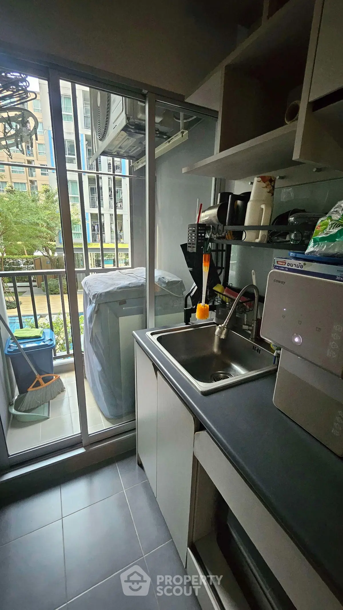 Modern kitchen with balcony view, sleek countertops, and ample storage in urban apartment