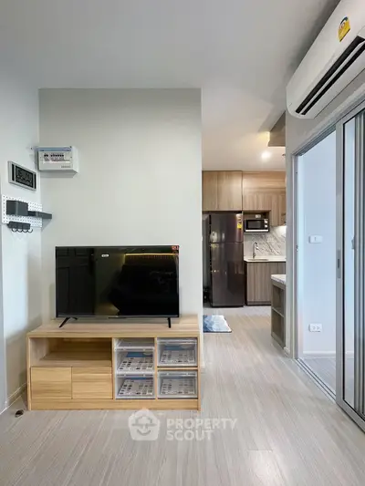 Modern living room with sleek kitchen, featuring TV stand and stainless steel appliances.