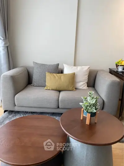 Stylish modern living room with cozy gray sofa and chic wooden coffee tables.