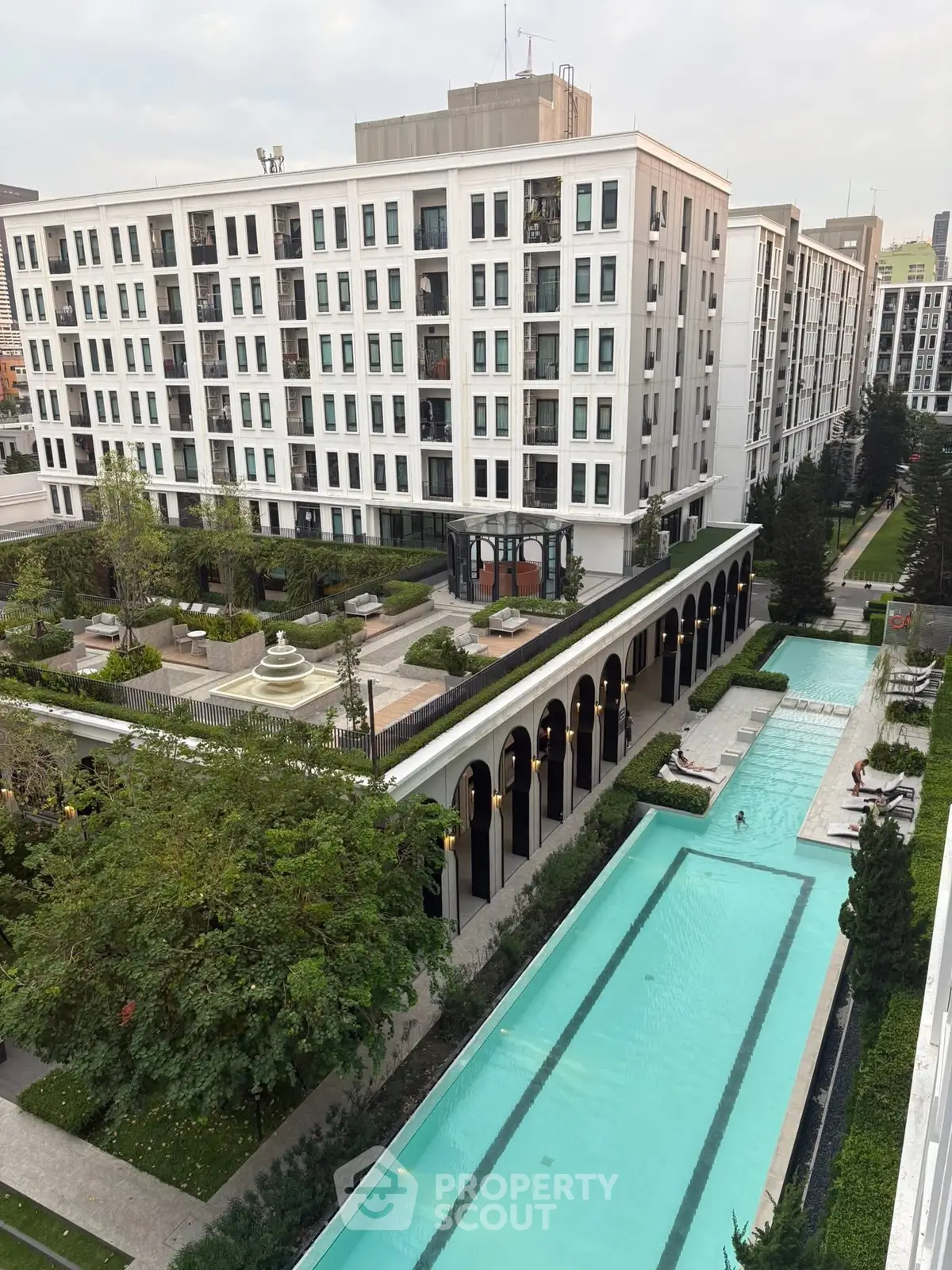 Luxurious apartment complex with stunning pool and lush gardens, offering modern urban living in a serene environment.