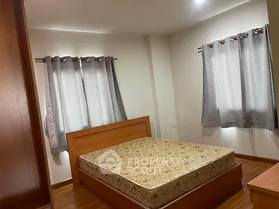 Spacious bedroom with wooden flooring and large windows for natural light.