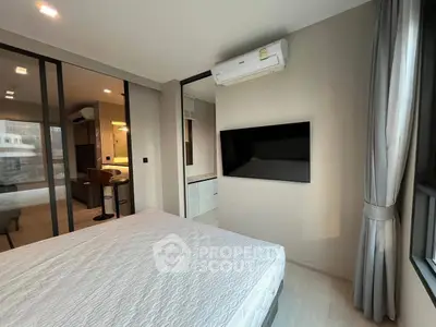 Modern bedroom with wall-mounted TV and air conditioning, adjacent to stylish kitchen area.