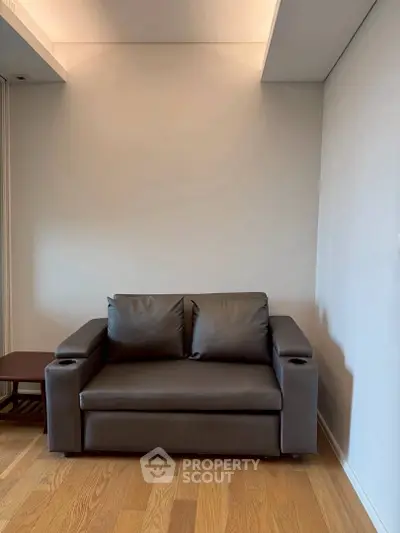 Modern living room with sleek black sofa and wooden flooring, perfect for contemporary urban living.