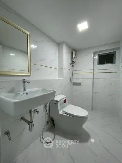 Modern bathroom with sleek white fixtures and elegant marble tiles.