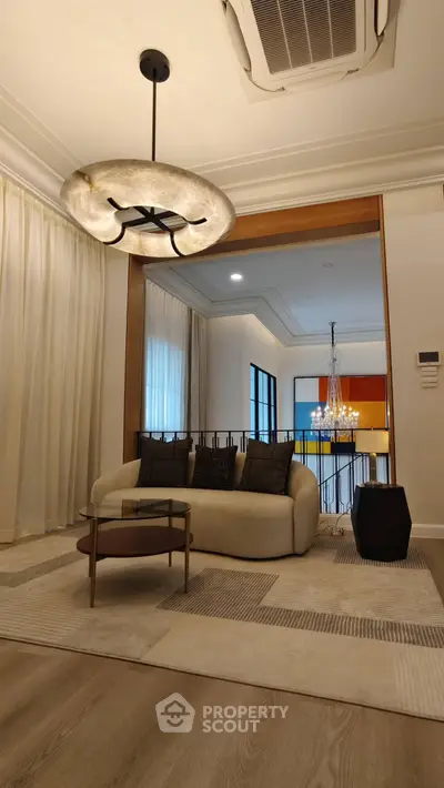 Elegant living room with modern chandelier and cozy seating area, perfect for relaxation and entertaining.