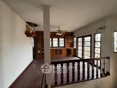 Spacious living room with wooden flooring and built-in cabinets, featuring large windows for natural light.