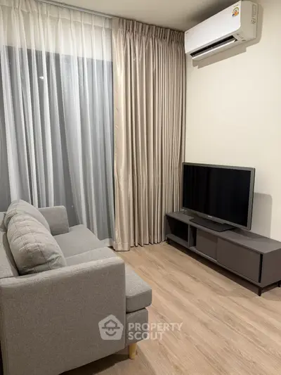Modern living room with sleek sofa, TV, and air conditioning unit, perfect for cozy relaxation.