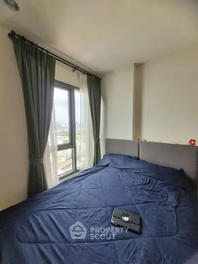 Cozy bedroom with city view, featuring a comfortable bed and large window with curtains.