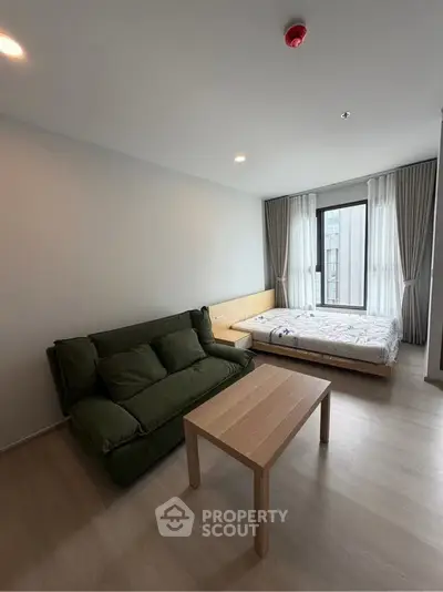 Modern studio apartment with cozy living area and large window view.