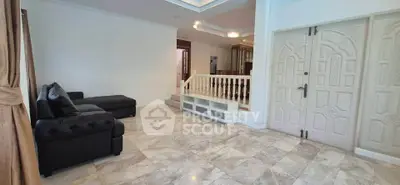 Spacious living room with elegant marble flooring and stylish black sofa in a modern home.