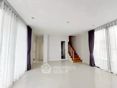 Spacious modern living room with large windows and elegant staircase