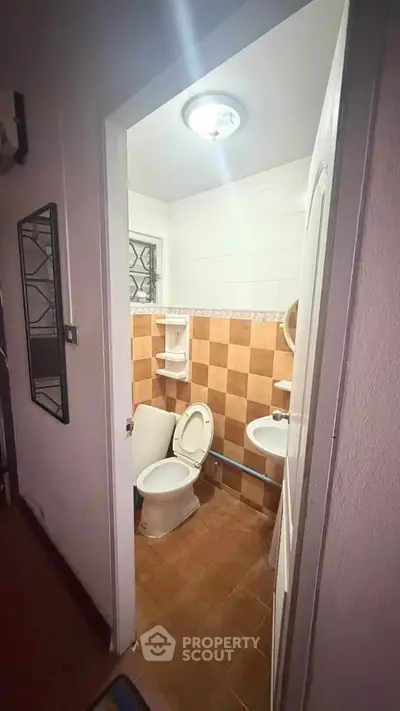 Cozy bathroom with tiled walls and compact layout, featuring a toilet and sink.