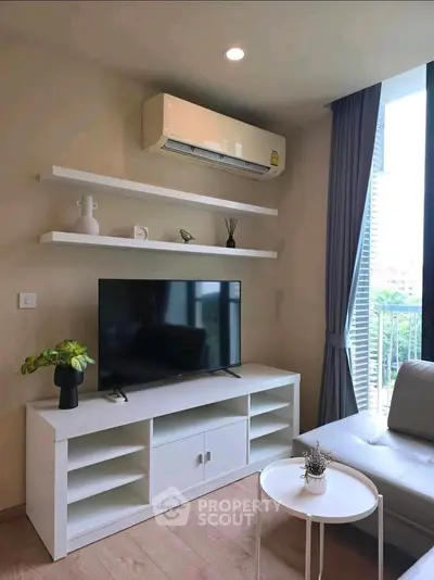 Modern living room with sleek furniture and natural light, featuring a wall-mounted TV and air conditioning.