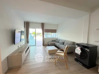 Spacious living room with modern furniture and large windows opening to a balcony.