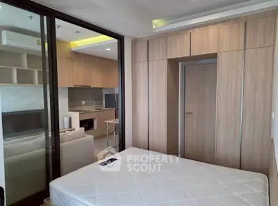 Modern bedroom with wooden wardrobe and open kitchen layout in a stylish apartment.