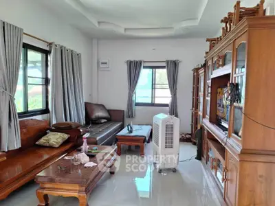 Spacious living room with wooden furniture and large windows for natural light.
