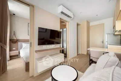 Modern apartment interior with open living room and kitchen, featuring sleek furniture and natural light.
