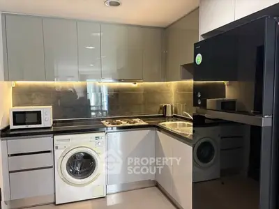 Modern kitchen with sleek appliances, washing machine, and stylish cabinetry.
