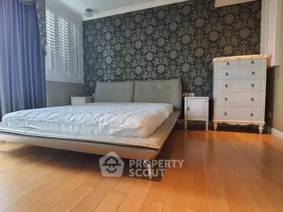 Elegant bedroom with stylish wallpaper and modern furniture, featuring a sleek bed and wooden flooring.