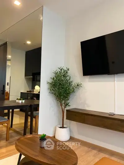 Modern living room with wall-mounted TV, stylish furniture, and indoor plant for a cozy ambiance.