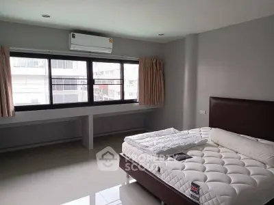Spacious bedroom with large windows and modern air conditioning unit.