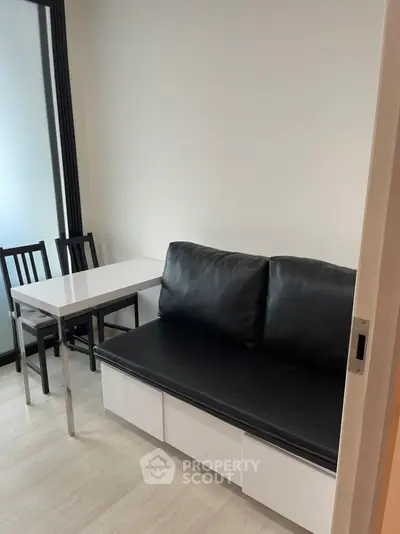 Cozy small living area with black leather sofa and dining table, perfect for compact spaces.