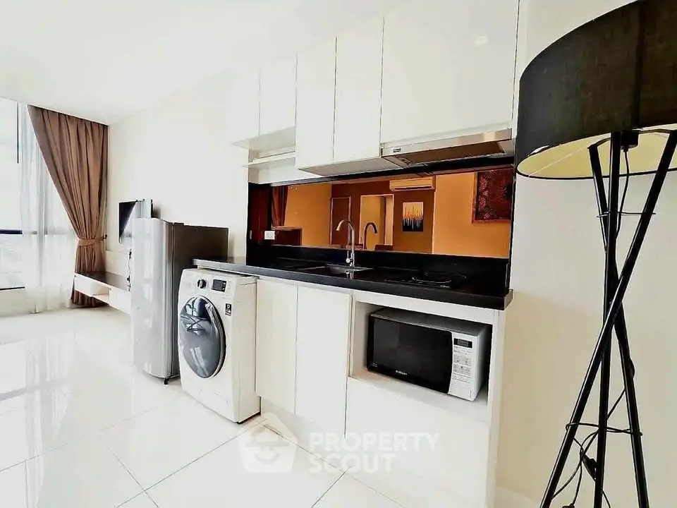 Modern kitchen with sleek appliances and glossy white cabinets in a bright apartment.