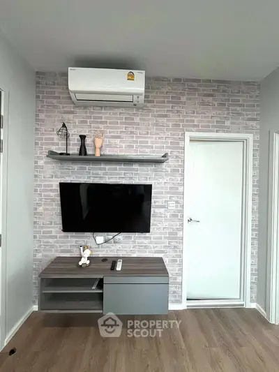 Modern living room with wall-mounted TV and air conditioning, featuring stylish brick accent wall.