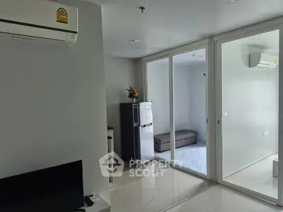 Modern apartment interior with air conditioning and sliding glass doors leading to a cozy balcony.