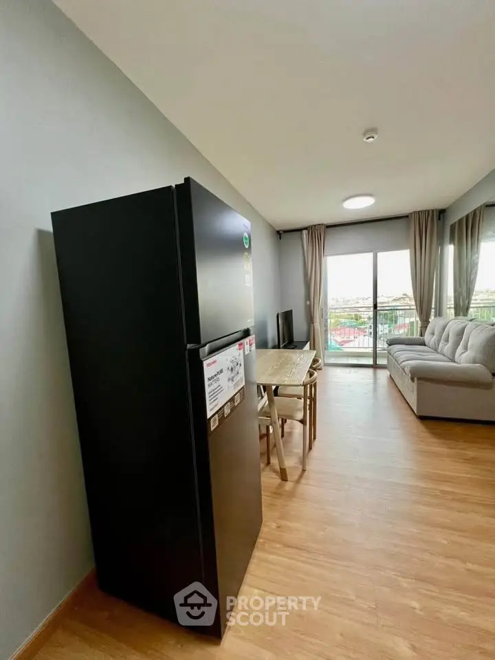 Modern living room with sleek black fridge and spacious balcony view.