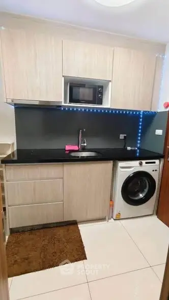Modern kitchen with sleek cabinetry, built-in microwave, and washing machine, perfect for urban living.