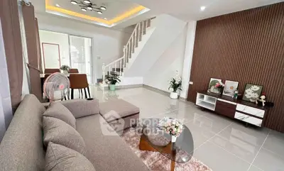 Modern living room with stylish decor and open layout, featuring a cozy sofa and elegant staircase.
