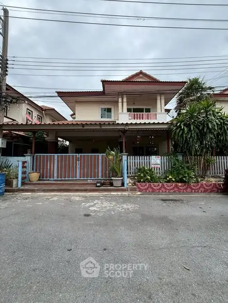 Charming two-story house with gated entrance and lush garden in a serene neighborhood.