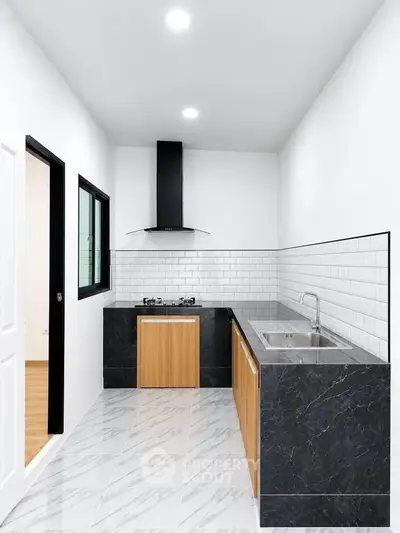 Modern kitchen with sleek black countertops and gas stove in minimalist design.
