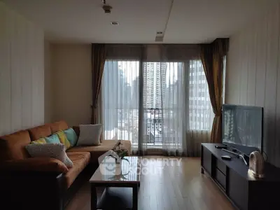 Spacious living room with city view, featuring cozy sofa and modern entertainment setup.