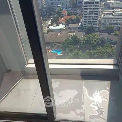 High-rise balcony with city view and sunlight reflection on floor.