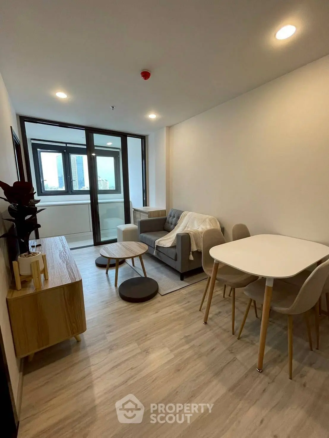 Modern living room with cozy sofa and dining area, featuring large windows and stylish decor.