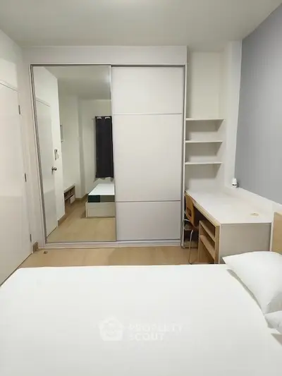 Modern bedroom with mirrored closet and study desk, perfect for urban living.