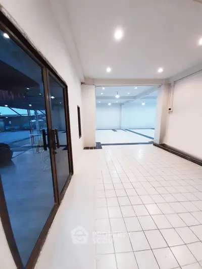 Spacious white-tiled interior with large windows and modern lighting, perfect for versatile use.