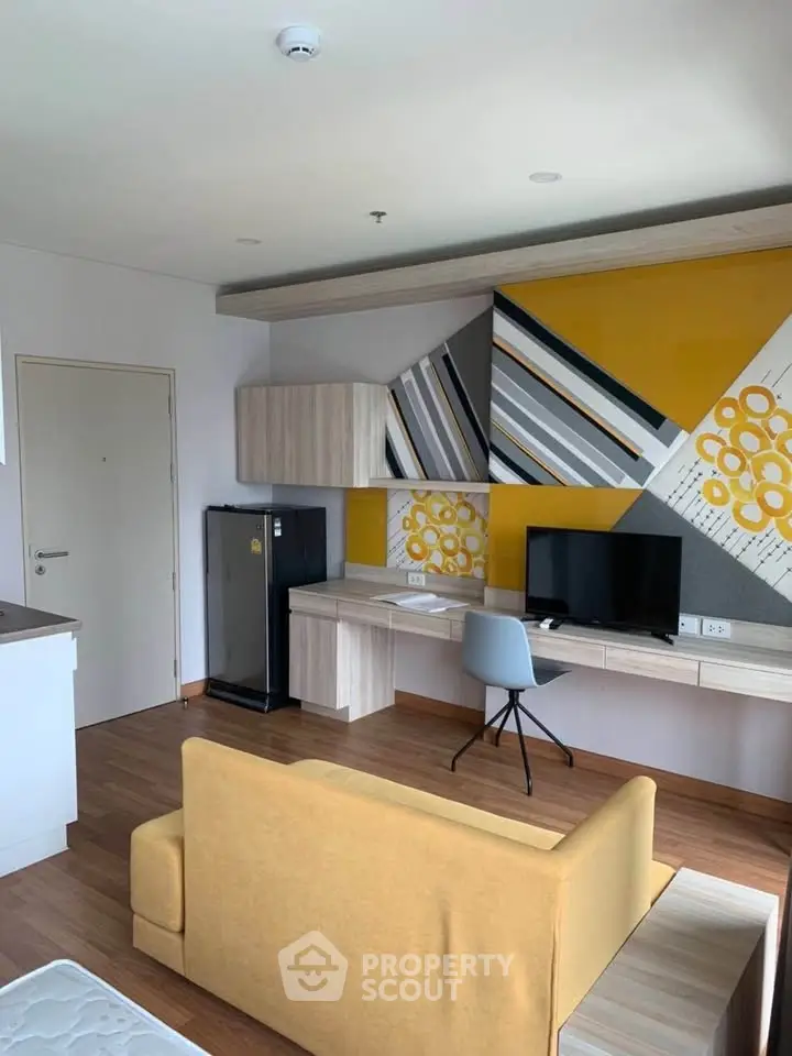 Modern living room with stylish decor and workspace, featuring a yellow sofa and wall art.