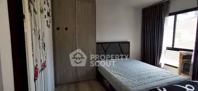 Cozy bedroom with modern wardrobe and large window offering natural light.