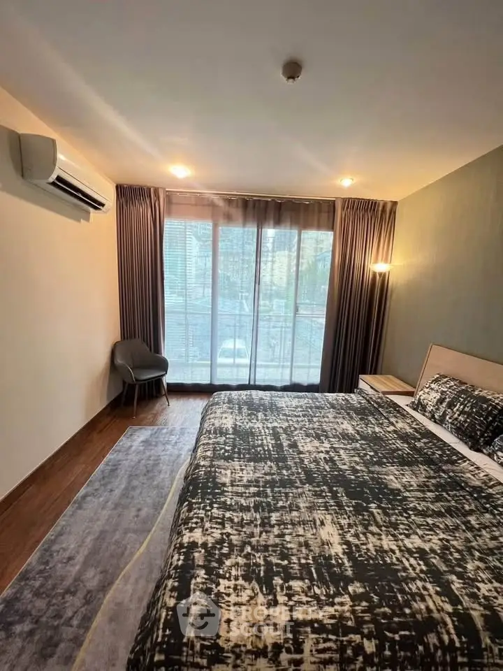 Spacious bedroom with large window and modern decor in a stylish apartment.