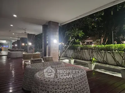 Elegant outdoor seating area with modern wicker furniture and lush greenery at night.